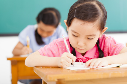 children in classroom with pen in hand